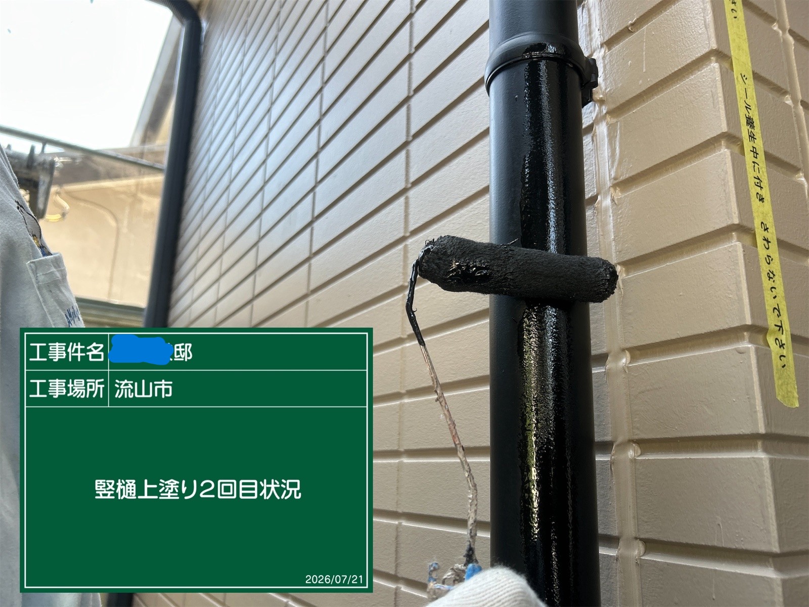 ローラーで竪樋を塗装する様子